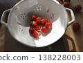 Fresh red strawberries in vintage ceramic colander on wooden table. Organic berries in white stoneware bowl with sunlight shadows, inspired by wabi-sabi and cottagecore aesthetic. 138228003