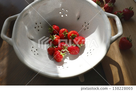 Fresh red strawberries in vintage ceramic colander on wooden table. Organic berries in white stoneware bowl with sunlight shadows, inspired by wabi-sabi and cottagecore aesthetic. Fresh red strawberries in vintage ceramic colander on wooden table. Organic berries in white stoneware bowl with sunlight shadows, inspired by wabi-sabi and cottagecore aesthetic. 138228003