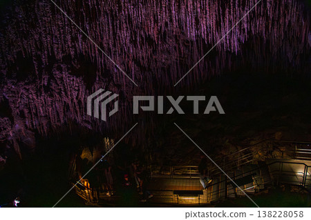 壯麗的鐘乳石與石筍群在紫色與琥珀色燈光交織下,佈滿了整個地底洞穴 138228058