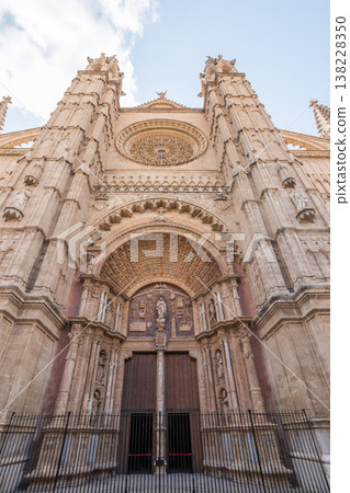 Detailed view of La Seu Cathedral facade in Palma de Mallorca, Spain, featuring intricate stone carvings, rose window and grand wooden doors Detailed view of La Seu Cathedral facade in Palma de Mallorca, Spain, featuring intricate stone carvings, rose window and grand wooden doors 138228350