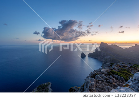 Scenic view of Mallorca northwest coastline at sunrise with rugged cliffs, calm Mediterranean Sea, distant horizon, and soft clouds lit by early morning light Scenic view of Mallorca northwest coastline at sunrise with rugged cliffs, calm Mediterranean Sea, distant horizon, and soft clouds lit by early morning light 138228357