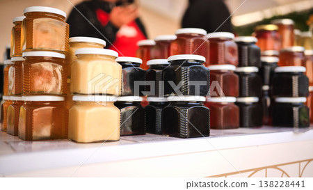 Honey jars, various shades of natural honey, stacked on a market stall shelf Honey jars, various shades of natural honey, stacked on a market stall shelf 138228441