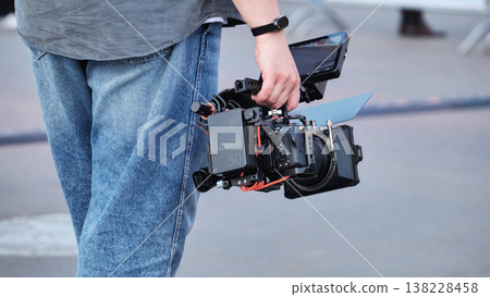 Videographer carrying professional cinema camera rig filming for media production 138228458