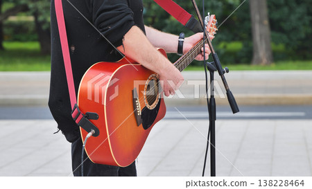 Street musician playing acoustic guitar outdoors providing live public entertainment Street musician playing acoustic guitar outdoors providing live public entertainment 138228464