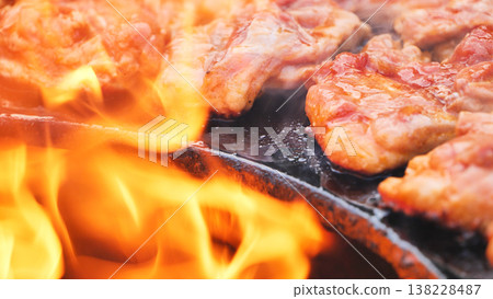 Grilling meat on a barbecue with open flames, cooking for a delicious summer meal Grilling meat on a barbecue with open flames, cooking for a delicious summer meal 138228487