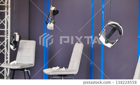 Virtual reality headsets hanging with chairs, ready for immersive metaverse gaming experience Virtual reality headsets hanging with chairs, ready for immersive metaverse gaming experience 138228558