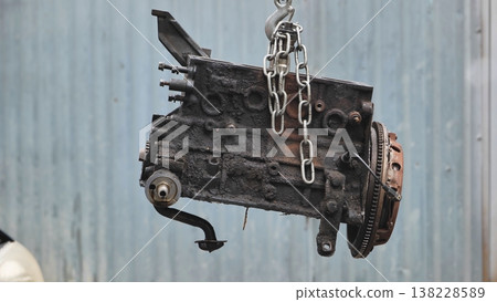 Car engine block hanging with chain during repair Car engine block hanging with chain during repair 138228589