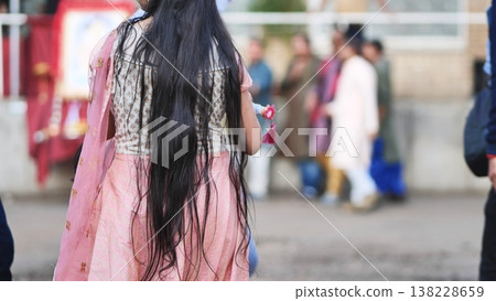 Woman with long dark hair celebrating Ganesh Chaturthi, holding a small decorative item 138228659