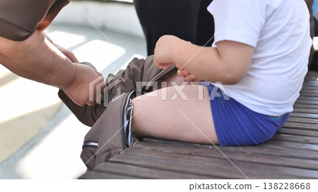 Parent helping young child getting dressed, putting on pants, care and support 138228668