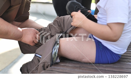 Child preparing for mobility, putting on prosthetic leg coverings for accessibility Child preparing for mobility, putting on prosthetic leg coverings for accessibility 138228697