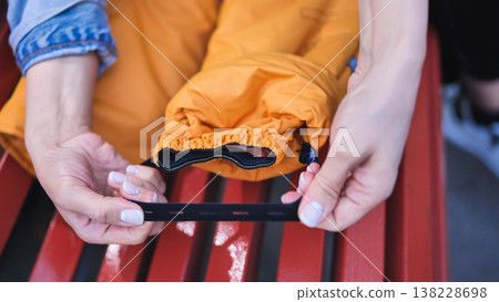 Hands stretching a black elastic belt with buttonholes for outdoor pants Hands stretching a black elastic belt with buttonholes for outdoor pants 138228698