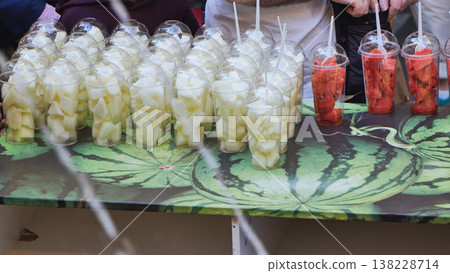 Seller serving refreshing melon and watermelon fruit cups 138228714