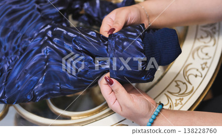 Person adjusting shiny navy blue winter jacket sleeve and cuff Person adjusting shiny navy blue winter jacket sleeve and cuff 138228760