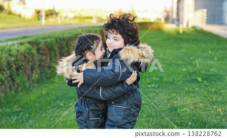 Happy children embracing outdoors, brother and sister hugging in warm winter coats Happy children embracing outdoors, brother and sister hugging in warm winter coats 138228762