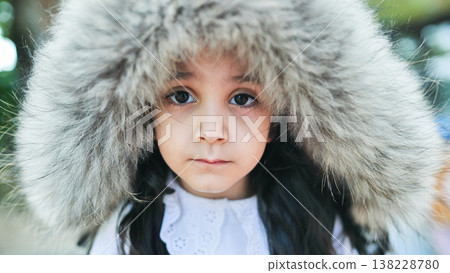 Young girl wearing fur hood showing winter warmth and childhood innocence portrait 138228780