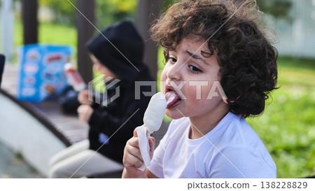 Child eating ice cream in a park, enjoying a summer treat during childhood Child eating ice cream in a park, enjoying a summer treat during childhood 138228829
