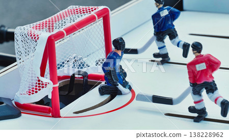 Table hockey game with miniature players and goalie in front of the net. Table hockey game with miniature players and goalie in front of the net. 138228962
