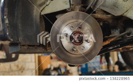 Mechanic replacing car disc brakes in a garage Mechanic replacing car disc brakes in a garage 138228965