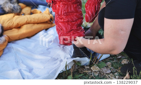 Adult helping child put on winter snowsuit and boots outdoors 138229037