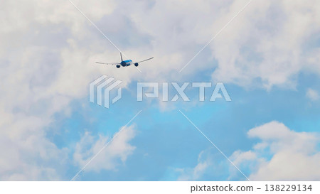 Passenger airplane flying away through white clouds in a blue sky 138229134