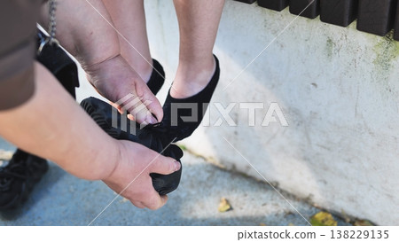 Adult hands helping a child tie shoe laces, showing care and support Adult hands helping a child tie shoe laces, showing care and support 138229135