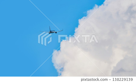 Passenger airplane flying over white cumulus clouds on clear blue sky Passenger airplane flying over white cumulus clouds on clear blue sky 138229139