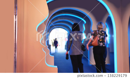 Visitors exploring head profile arches in a glowing blue light art exhibition Visitors exploring head profile arches in a glowing blue light art exhibition 138229179