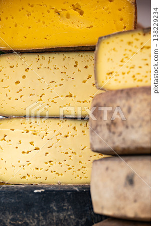 Stacked artisanal cheese wheels displaying holes and aged rinds for gourmet food 138229234