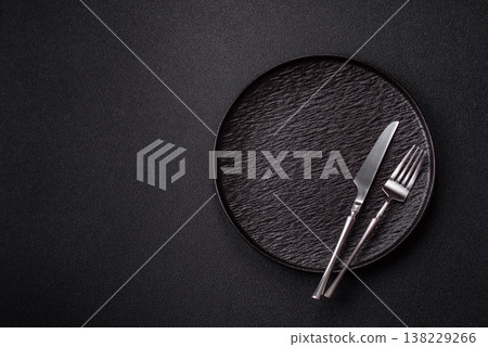 An empty round ceramic plate, knife, and fork as a dining table setting. An empty plate 138229266