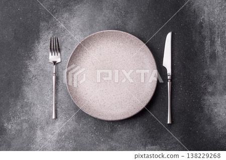 An empty round ceramic plate, knife, and fork as a dining table setting. An empty plate An empty round ceramic plate, knife, and fork as a dining table setting. An empty plate 138229268