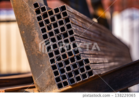 Metal square pipes in a stack, waiting for use at a construction site Metal square pipes in a stack, waiting for use at a construction site 138229365