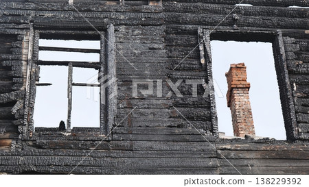 Burnt house facade showing charred wood wall and window frames after fire Burnt house facade showing charred wood wall and window frames after fire 138229392