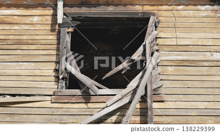 Charred window frame and broken pieces of wood on a damaged house after a fire Charred window frame and broken pieces of wood on a damaged house after a fire 138229399
