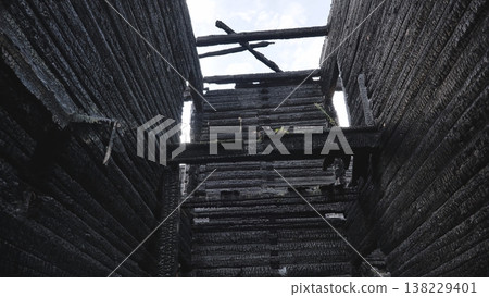 Charred remains of a burned wooden building, interior view looking up at the sky Charred remains of a burned wooden building, interior view looking up at the sky 138229401