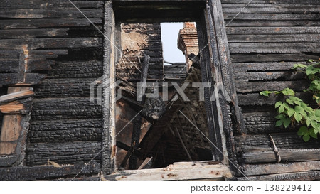Aftermath of a house fire with charred black wood and collapsed interior ruin Aftermath of a house fire with charred black wood and collapsed interior ruin 138229412