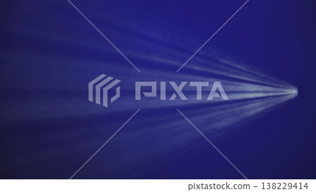 Volumetric light ray from a spotlight on a dark blue background with atmospheric haze. 138229414