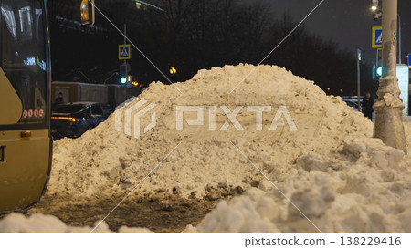 Urban snow pile accumulating on city street at night during winter season 138229416