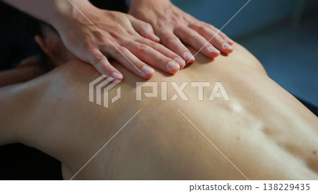 Hands performing relaxing back massage on person, feeling wellness and therapy 138229435
