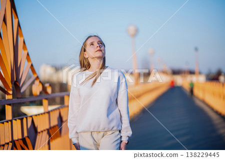 Young woman looking up, contemplating future while standing on urban bridge at sunset Young woman looking up, contemplating future while standing on urban bridge at sunset 138229445
