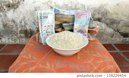 Large stacks of Venezuelan bolivar banknotes with a bowl of rice representing hyperinflation Large stacks of Venezuelan bolivar banknotes with a bowl of rice representing hyperinflation 138229454