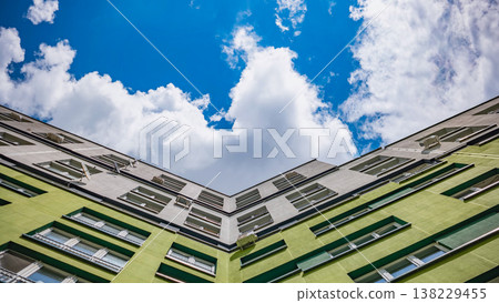 Modern architecture rising towards blue sky among white clouds on a sunny day Modern architecture rising towards blue sky among white clouds on a sunny day 138229455