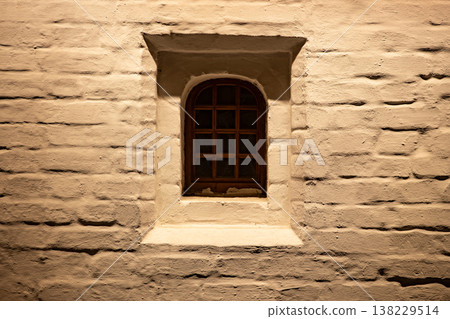 Arched wooden window set in a textured, illuminated brick wall at night Arched wooden window set in a textured, illuminated brick wall at night 138229514