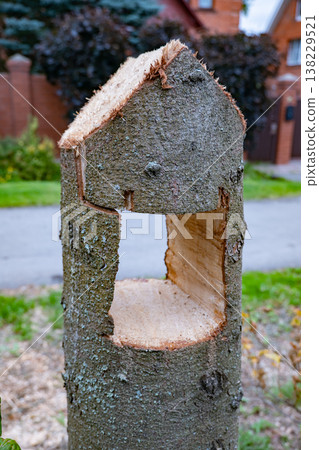 Carving a house shape into a tree trunk stump for creative garden decoration Carving a house shape into a tree trunk stump for creative garden decoration 138229521