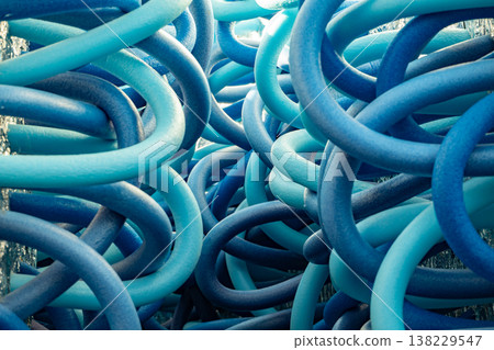 Tangled blue pool noodles forming an abstract pattern with intertwining curves 138229547