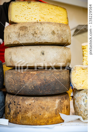 Artisan aged cheese wheels stacking on a white display in a market 138229564