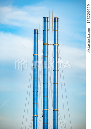 Blue industrial smokestacks rising against a clear sky, representing energy production 138229629