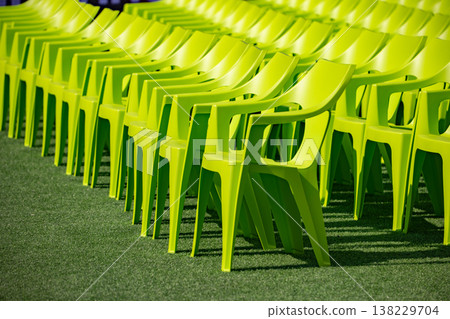 Rows of green plastic chairs on artificial turf creating a repetitive pattern Rows of green plastic chairs on artificial turf creating a repetitive pattern 138229704