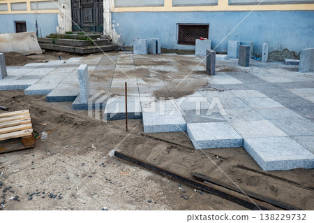 Urban paving installation, workers laying granite cobblestone on street ground Urban paving installation, workers laying granite cobblestone on street ground 138229732