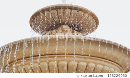 Water splashing from a decorative stone fountain bowl with carved details in a park Water splashing from a decorative stone fountain bowl with carved details in a park 138229960