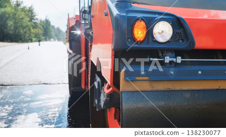 Road roller compacting hot asphalt on a new highway, illustrating infrastructure development Road roller compacting hot asphalt on a new highway, illustrating infrastructure development 138230077
